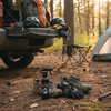 Camping scene with gear and a spray bottle on the ground in a forest. (Chuck's DE-FUNK Spray)