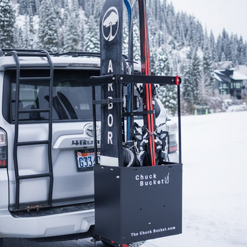 Skis on a  hitch rack attached to a vehicle in a snowy landscape